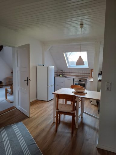 Kitchen Küche mit Tisch, Stühlen, Kühlschrank und Fenster in einem hellen Raum.